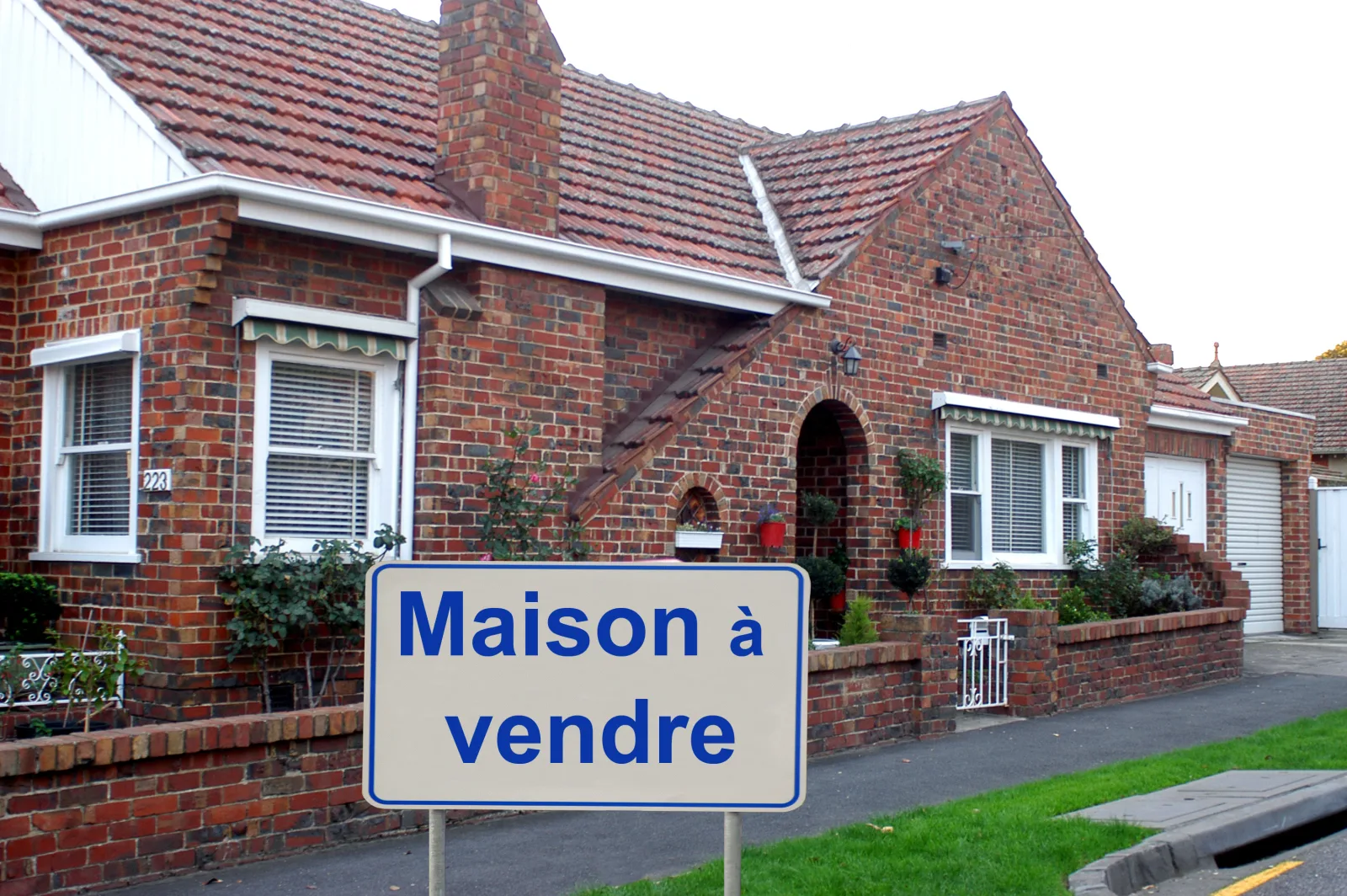 Maison en brique avec un panneau « Maison à vendre »